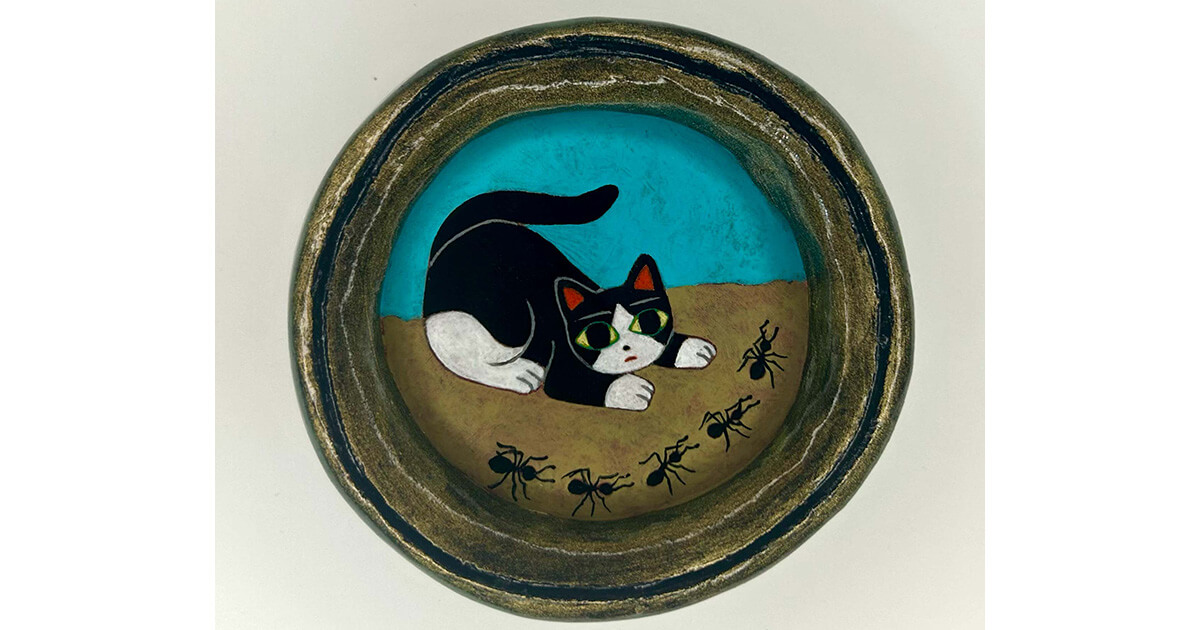 アリの行列を見つめる猫